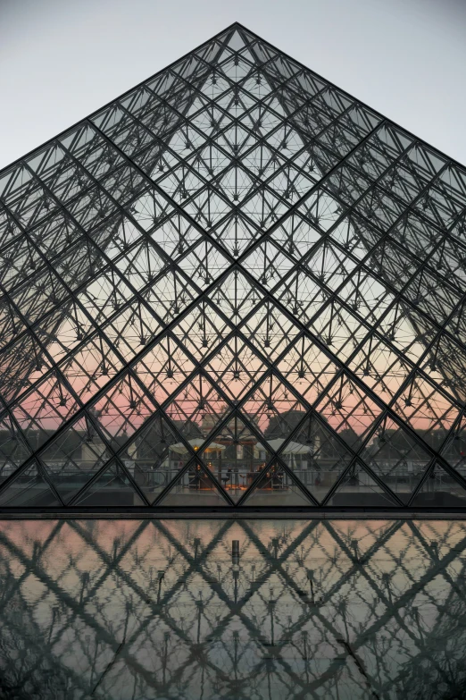 the glass pyramid in front of a building with a sky background