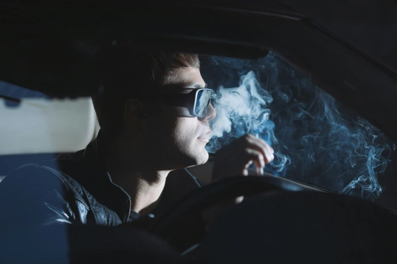 a man smoking in the passenger seat of his car