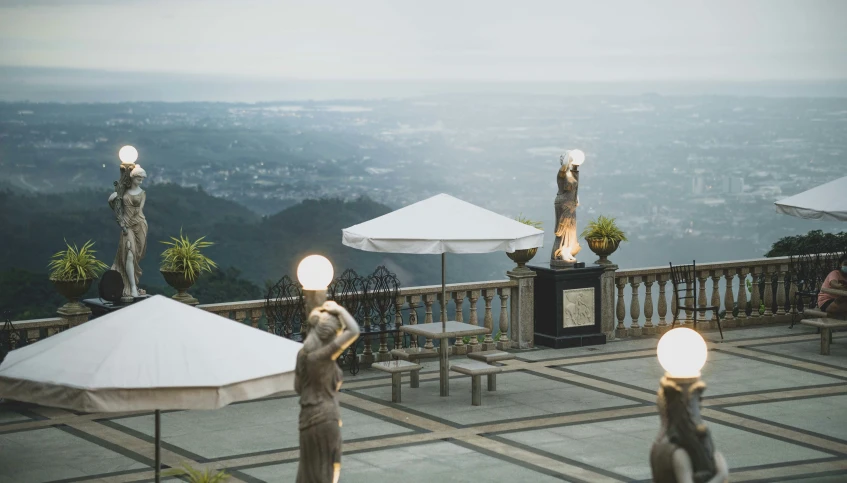 a view of a balcony with chairs, umbrellas and some lights