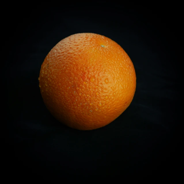 an orange sits on a dark background with bright spots