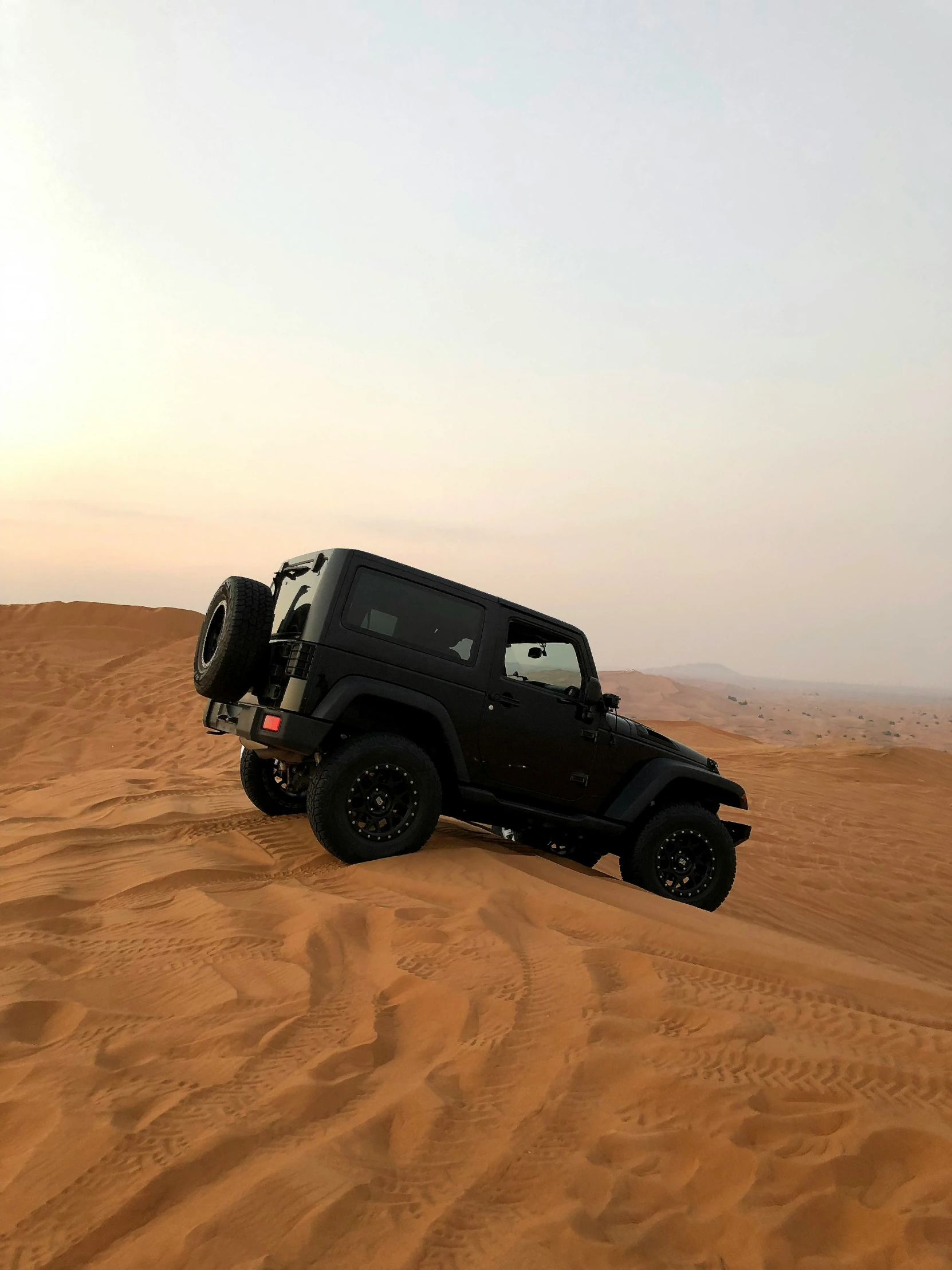 a jeep parked in a large open sandy field