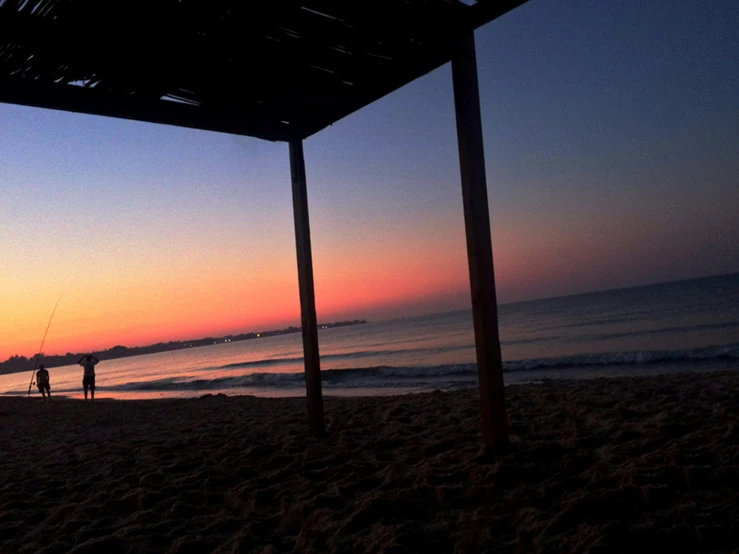 a person flying a kite at sunset on a beach