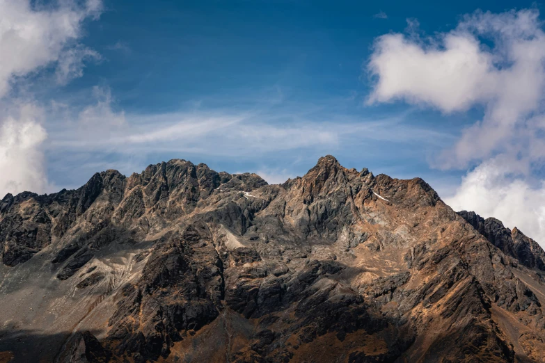 the top of mountains with white clouds in the sky