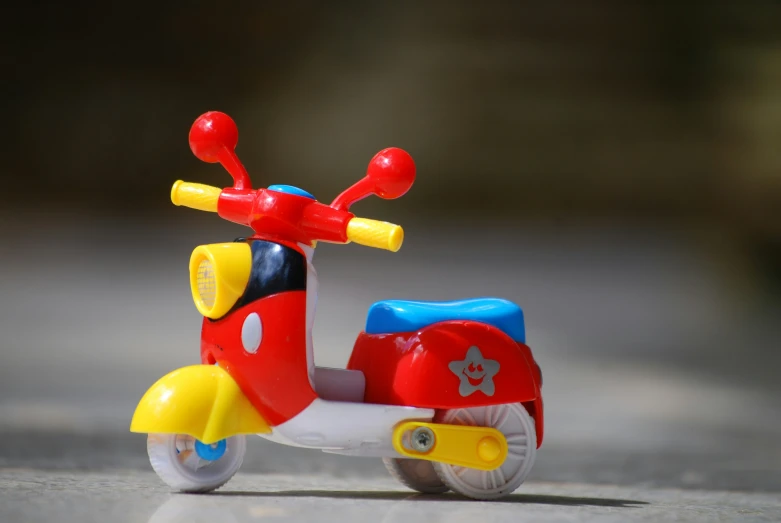 a red tricycle toy with yellow wheels