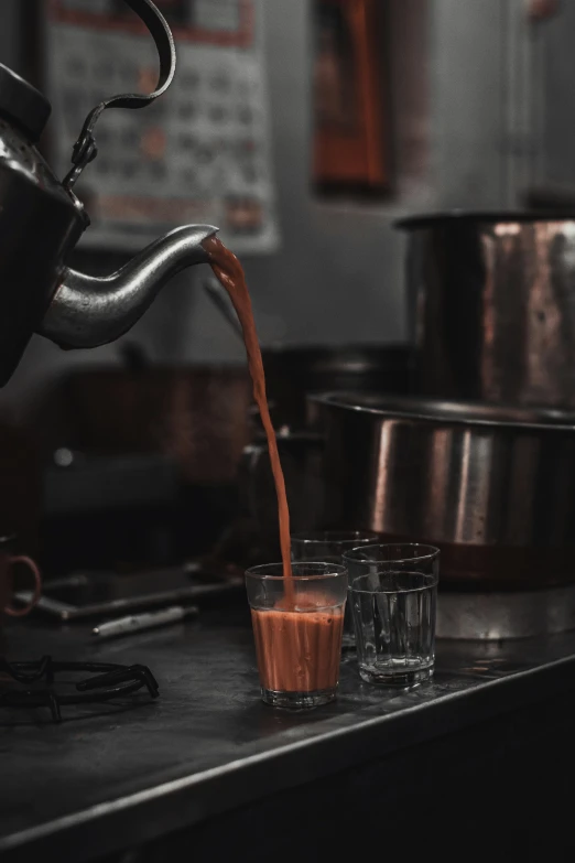 a pitcher pouring liquid in glasses on a table