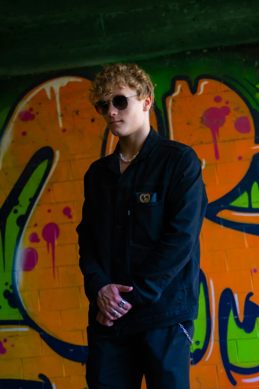 a man stands in front of a colorful graffiti wall