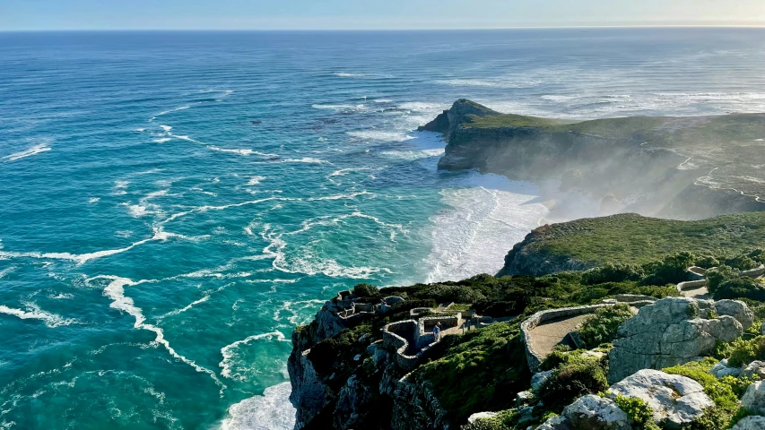 the ocean on a cliff next to a mountain