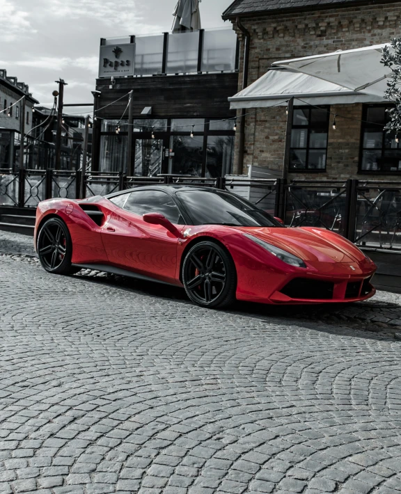 a red sports car is parked on a brick road