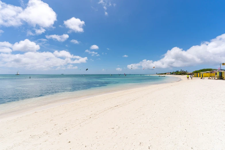 a white beach has a blue ocean with clouds in the background