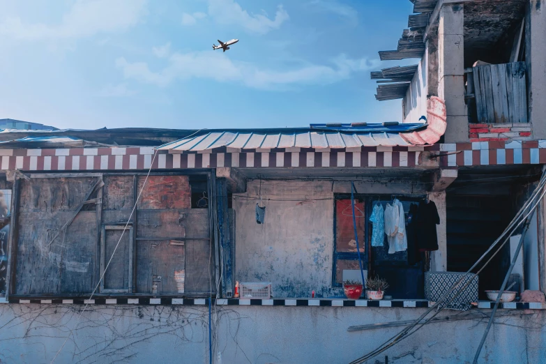 a plane flies above an abandoned building with windows