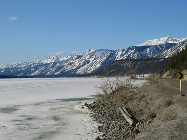 a road in the foreground with snowy mountains in the background