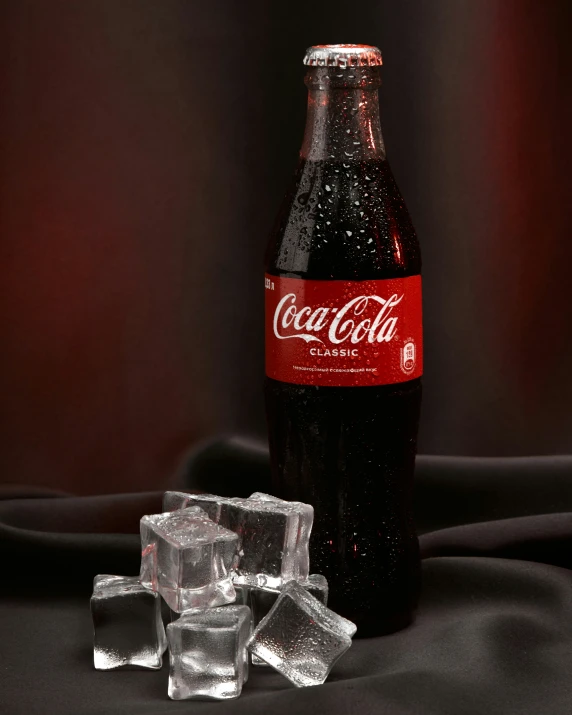 coca cola on a table with ice cubes and black background