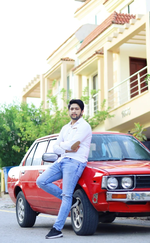 a man is posing in front of his car