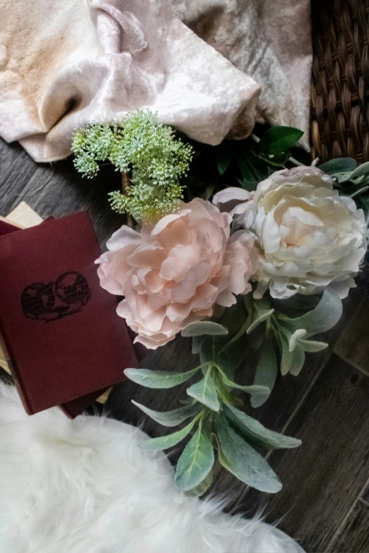 some flowers with a red book laying on a white rug