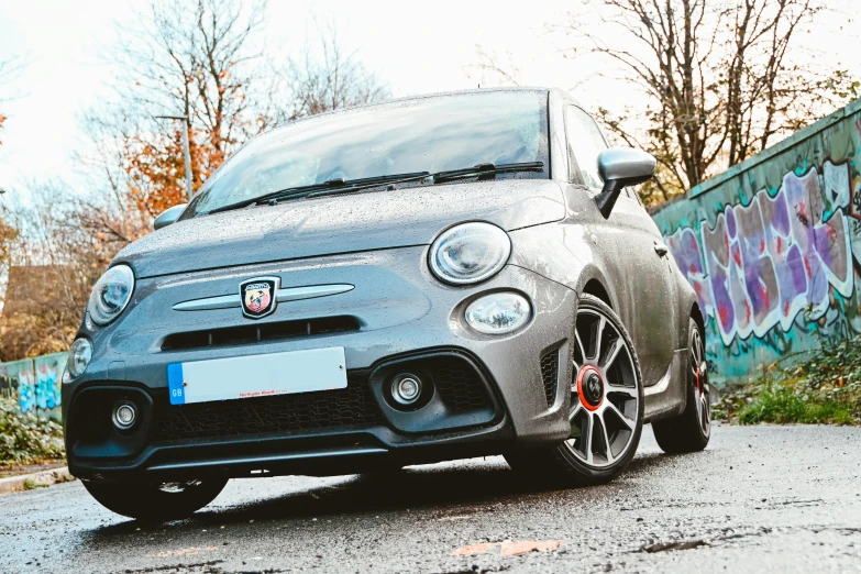 this is an image of a car parked in front of a graffiti covered wall