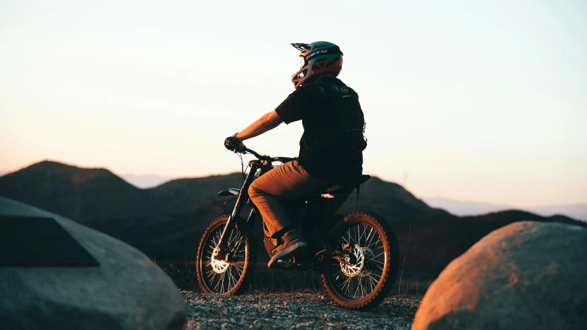 a young man in a helmet riding on his bicycle on the side of the road