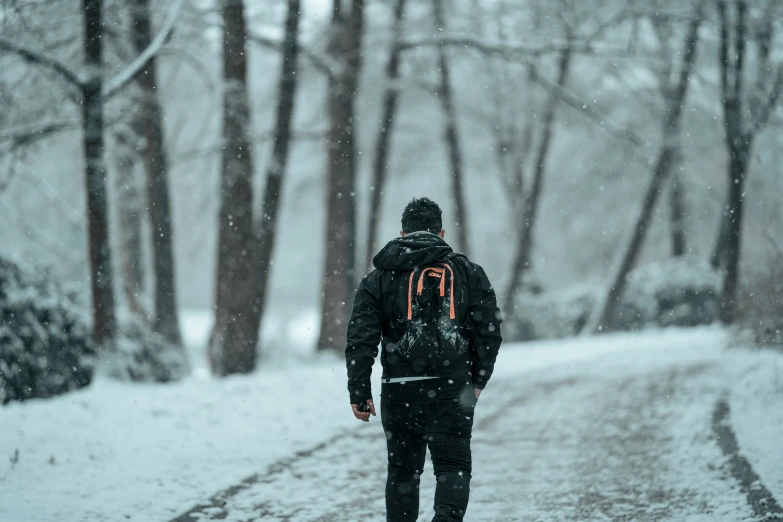 man walking in the snow down a road with a backpack on