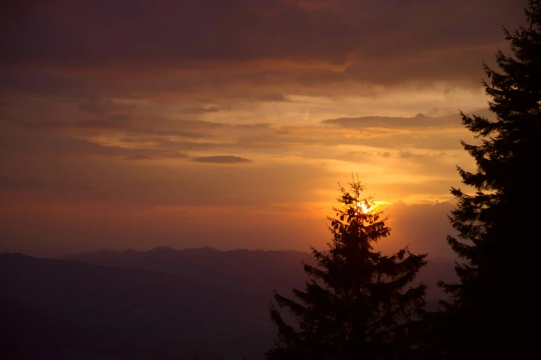 the sun rising in a dark sky with clouds