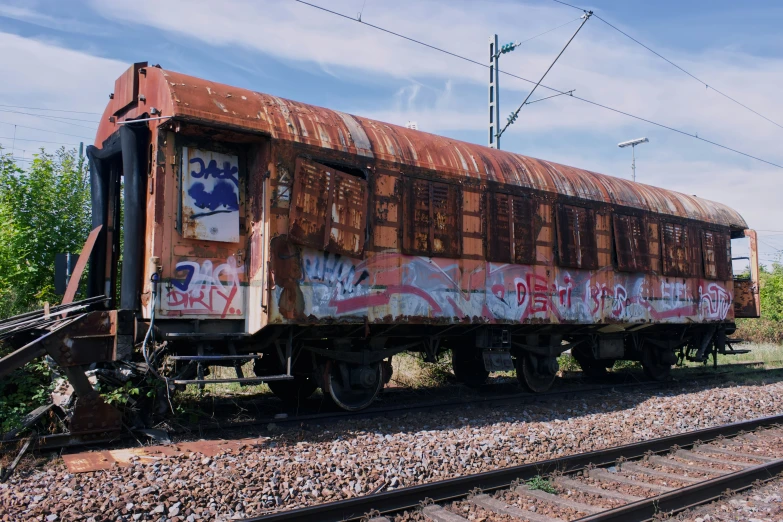 a rusty old train car with graffiti on it is sitting on the track
