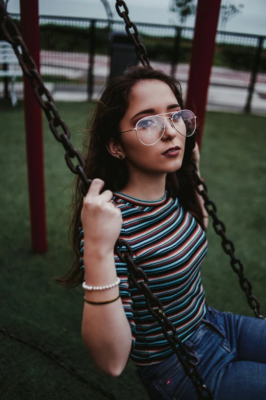 a young woman sitting on top of a swing