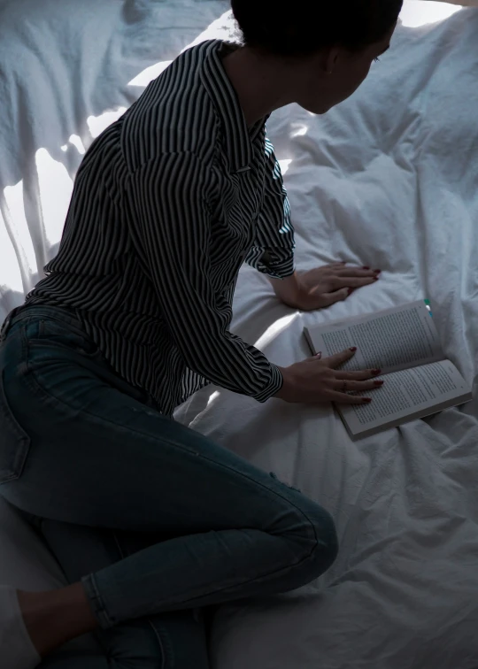 woman sits in bed while reading a book