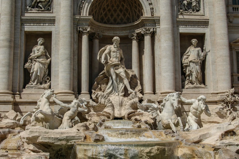 a fountain near a building with statues on top