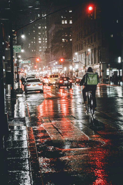 someone rides their bike through the city on a rainy day