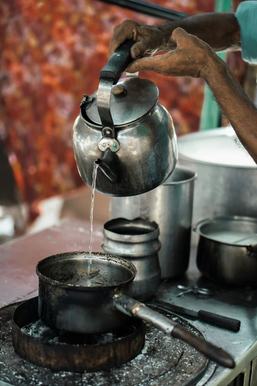 a woman filling her kettle with water from a burner