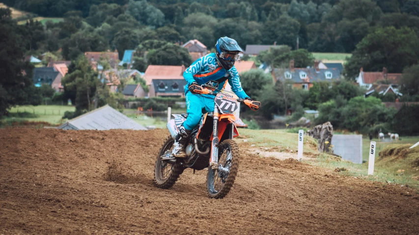 a motor cross rider races on dirt on a farm field