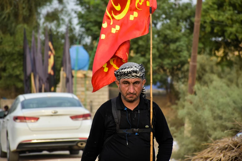 a man with a turban walks on the street holding a flag