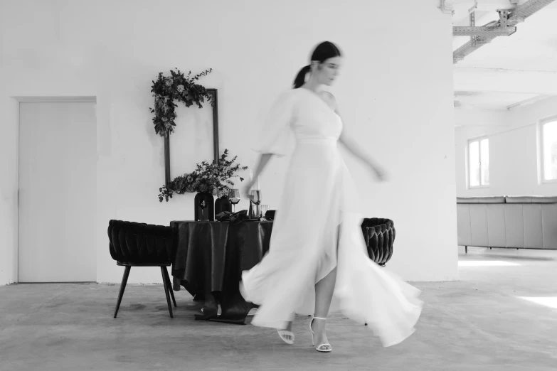 the woman is walking across the room carrying her wedding dress