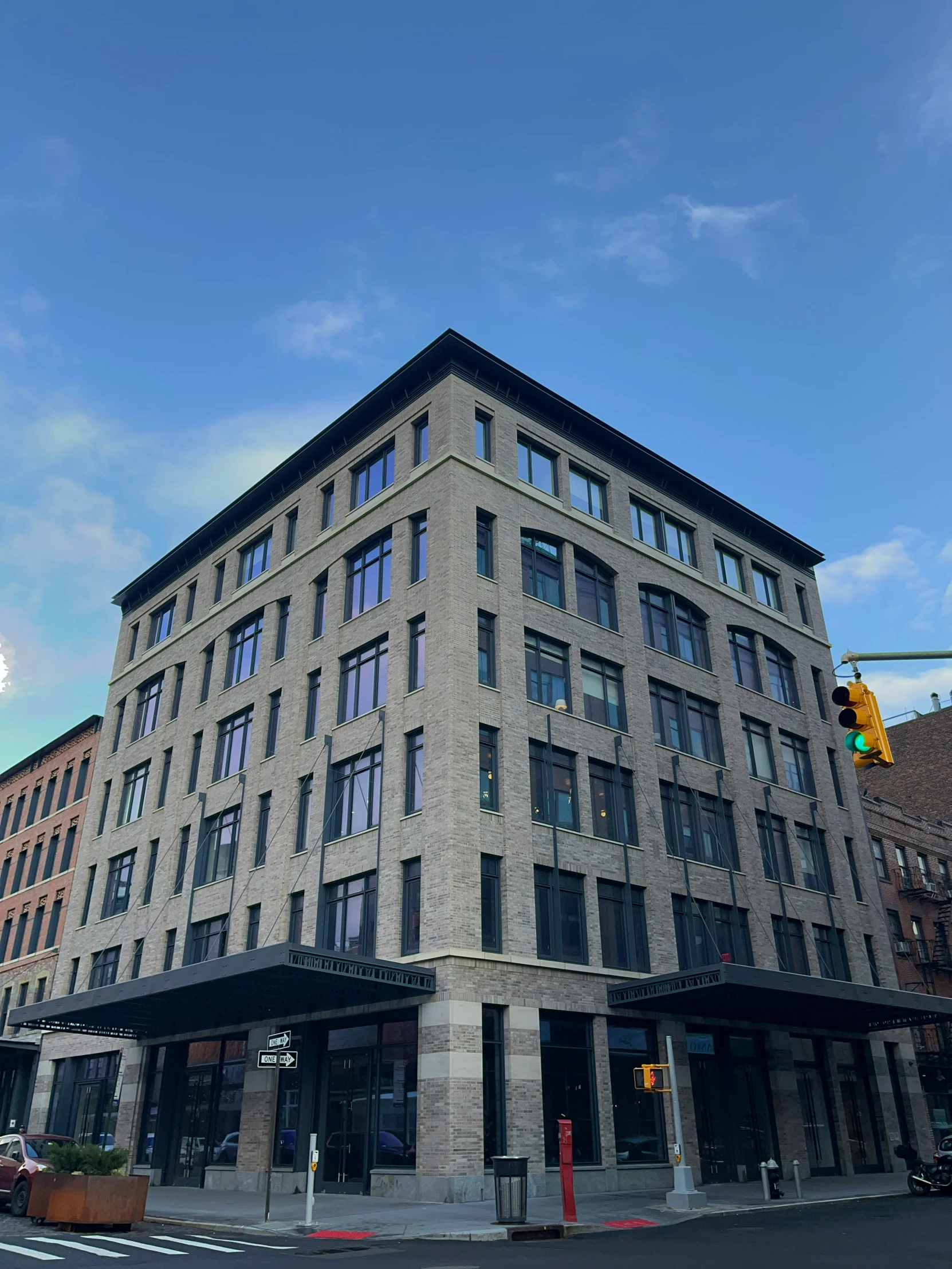 a grey brick building with an intersection and traffic light in front