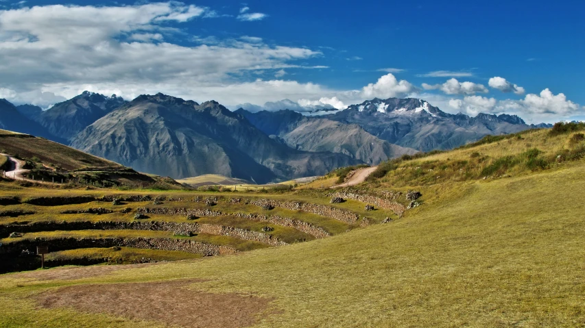 a green field filled with lots of dirt next to mountains