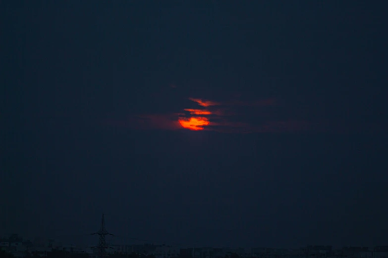 a red moon with the sun behind it in the sky