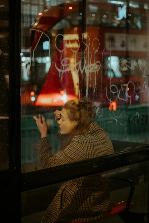 a woman leaning against a window in a city at night