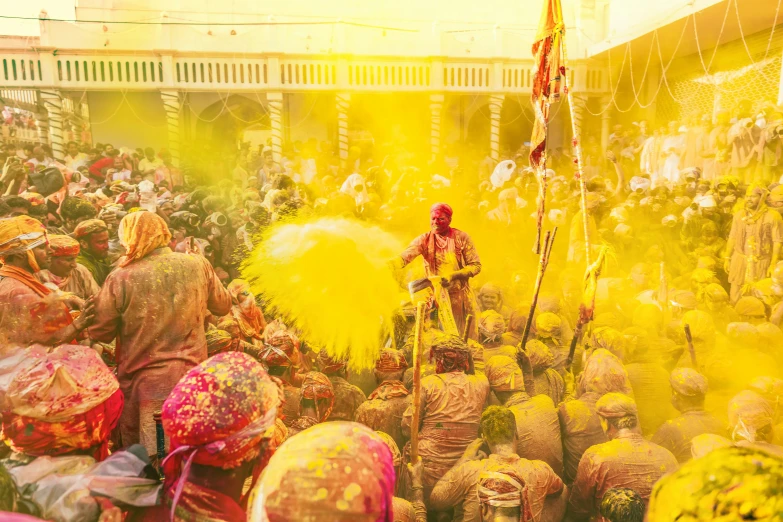 a crowd is throwing yellow powder around on the ground