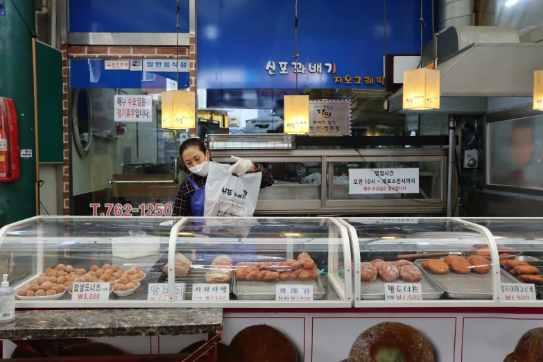 the woman behind the counter is working on the donuts