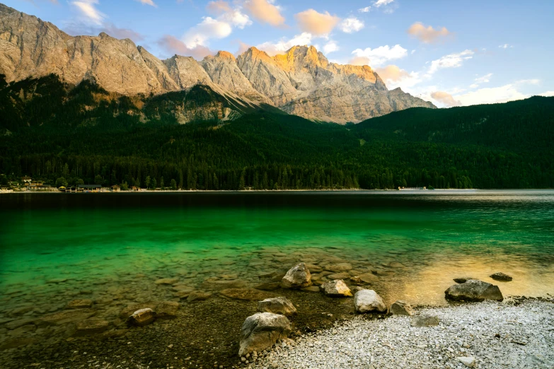 the water has clear green colors and is reflecting the mountains