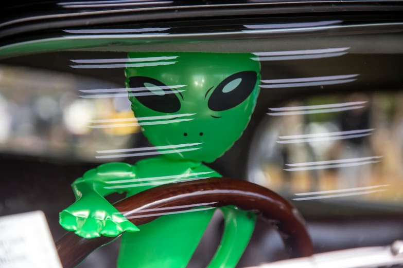 a green alien head sitting in the back of a car