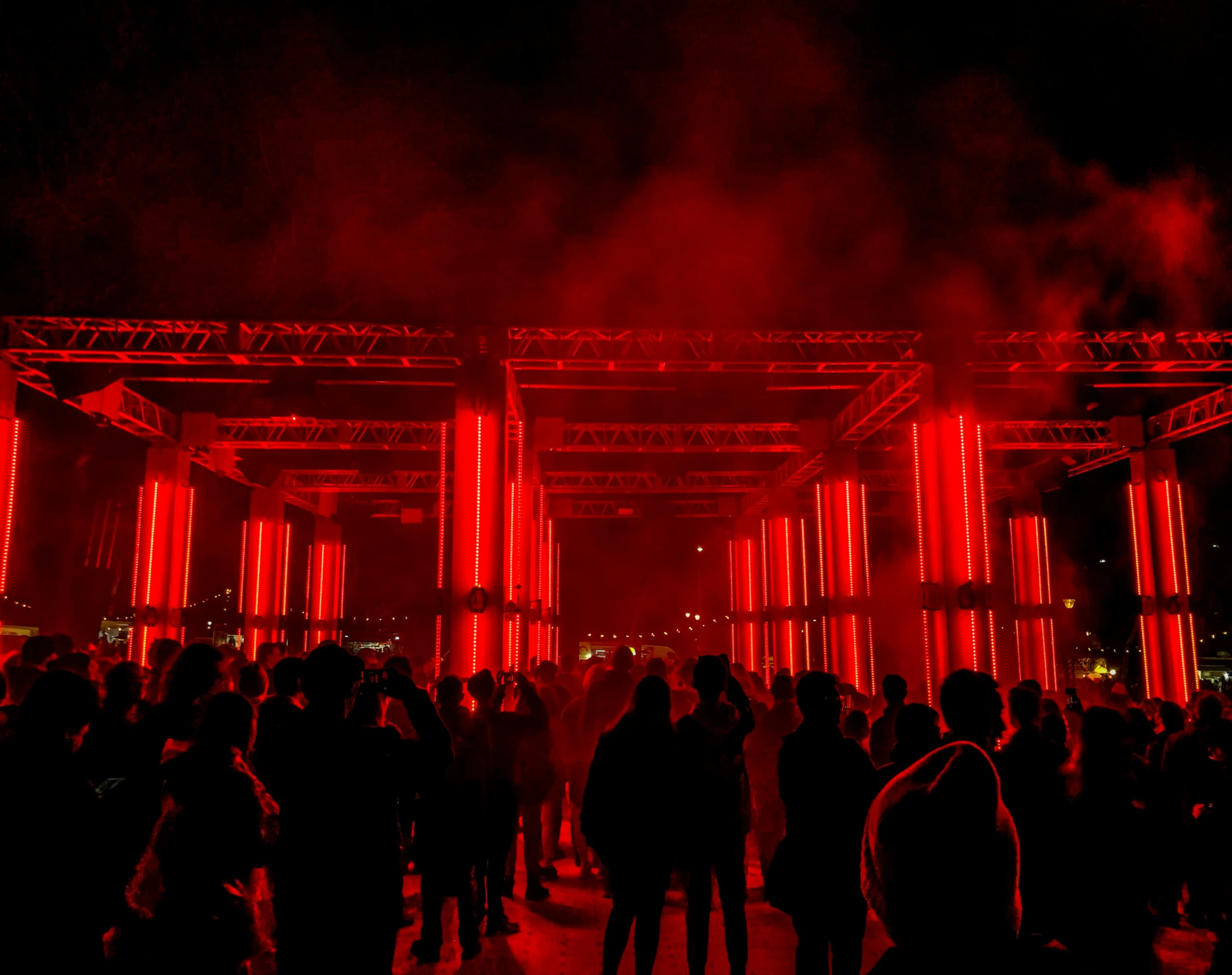 a group of people gathered under a stage covered in red lights