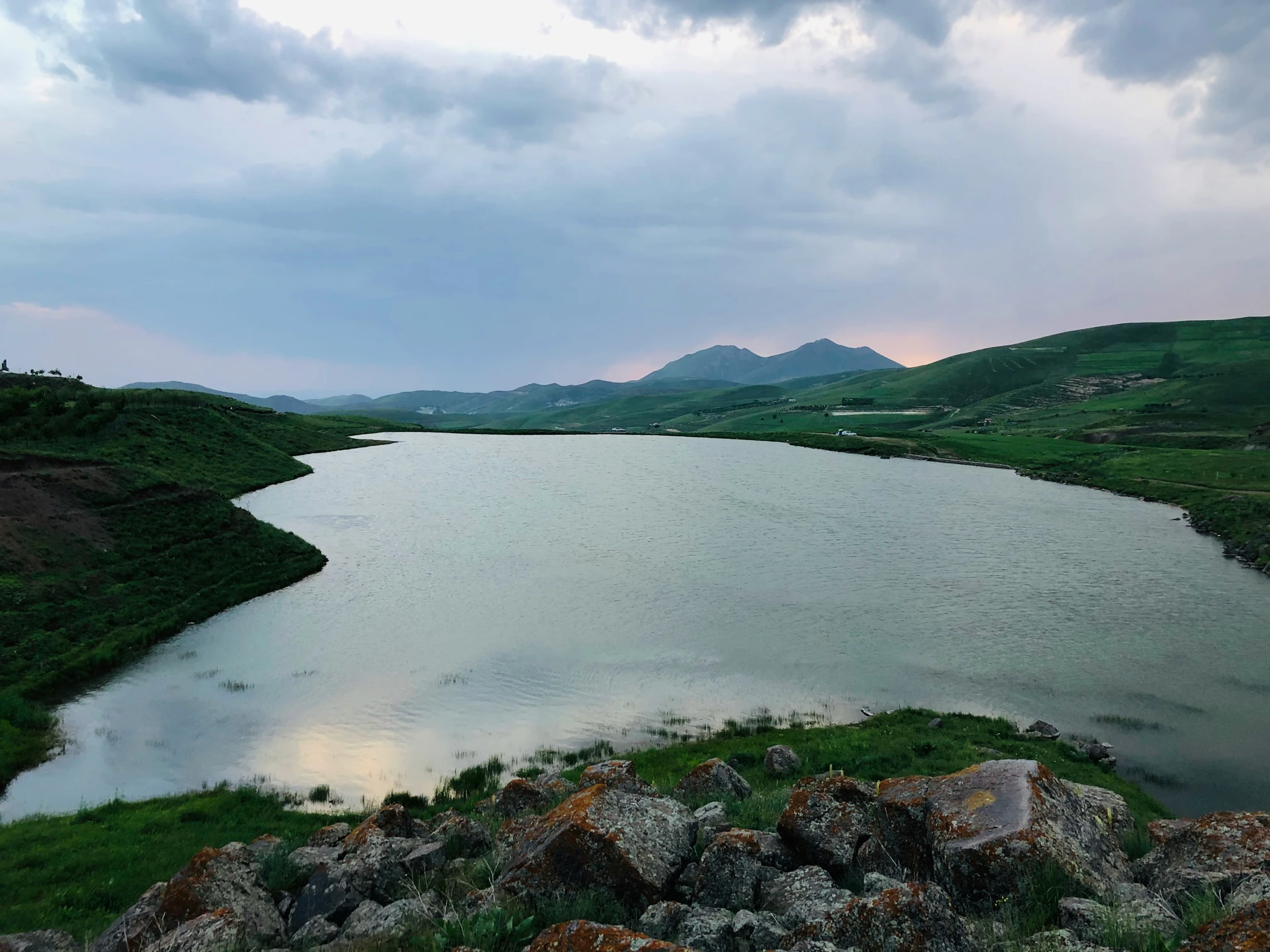 a body of water sitting next to a lush green hillside