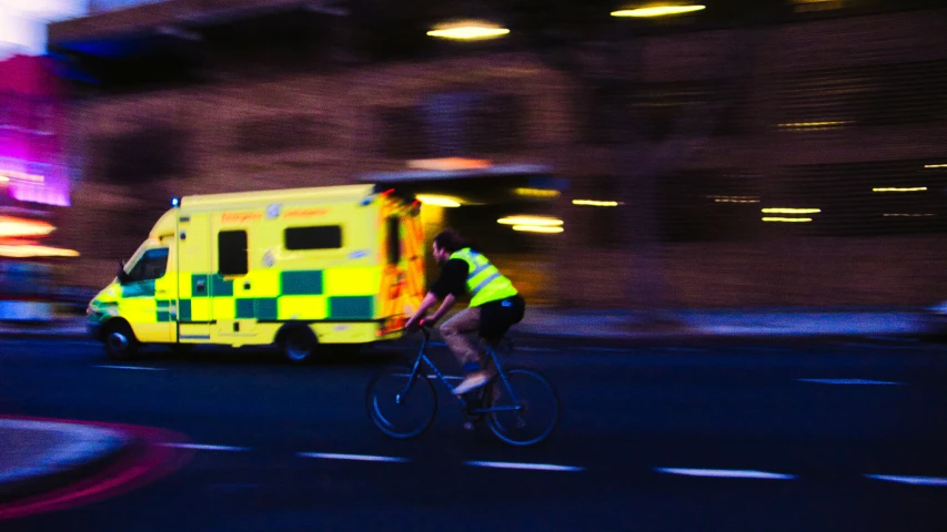 an ambulance with a man on a bike passing