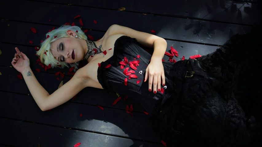 a blonde woman laying on the ground with roses and petals in her hair