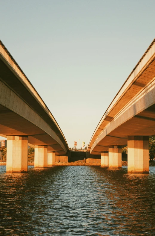 two highway bridges are seen from below the water