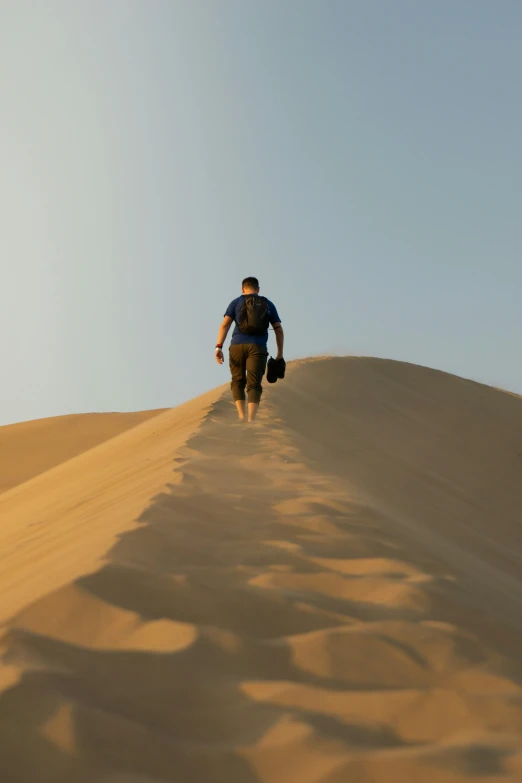 a man walking up a hill in the sand