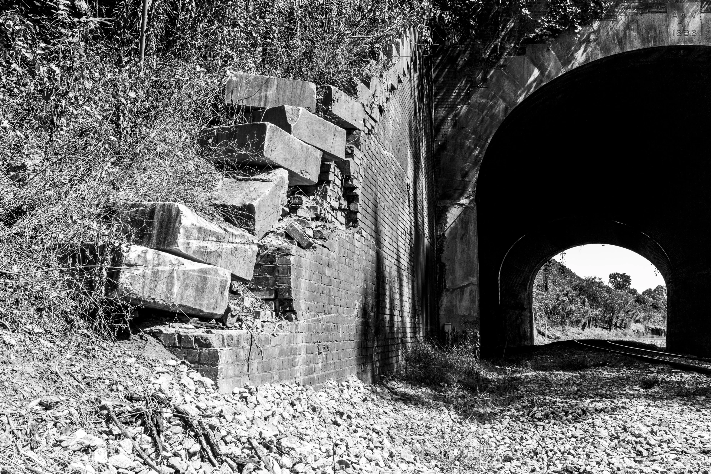 an old, crumbling looking train tunnel sits on top of a hill