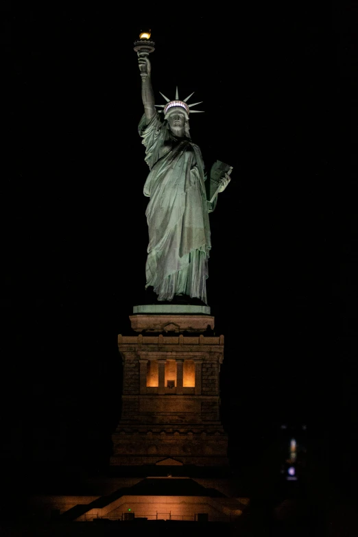 the statue of liberty lit up with a night sky