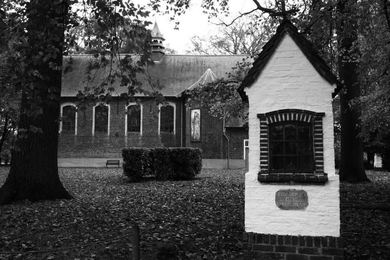 black and white po of a brick building in autumn with foliage around the windows