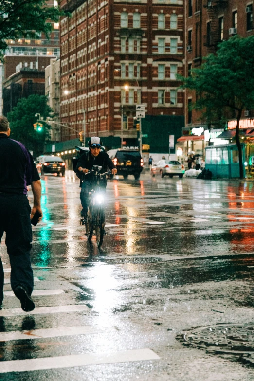 two men walking in the rain on a bike with headlights on