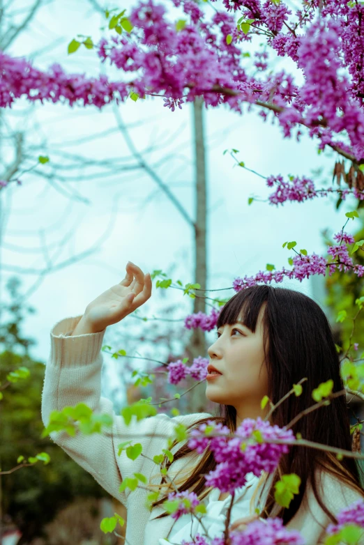 a woman standing next to purple flowers in the wind